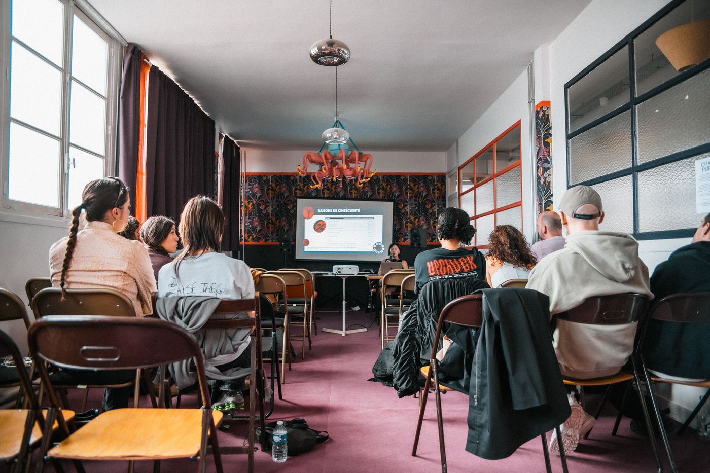 Une formation Consentis en salle : le public assis de dos, face à l'intervenante et à l'écran de présentation.